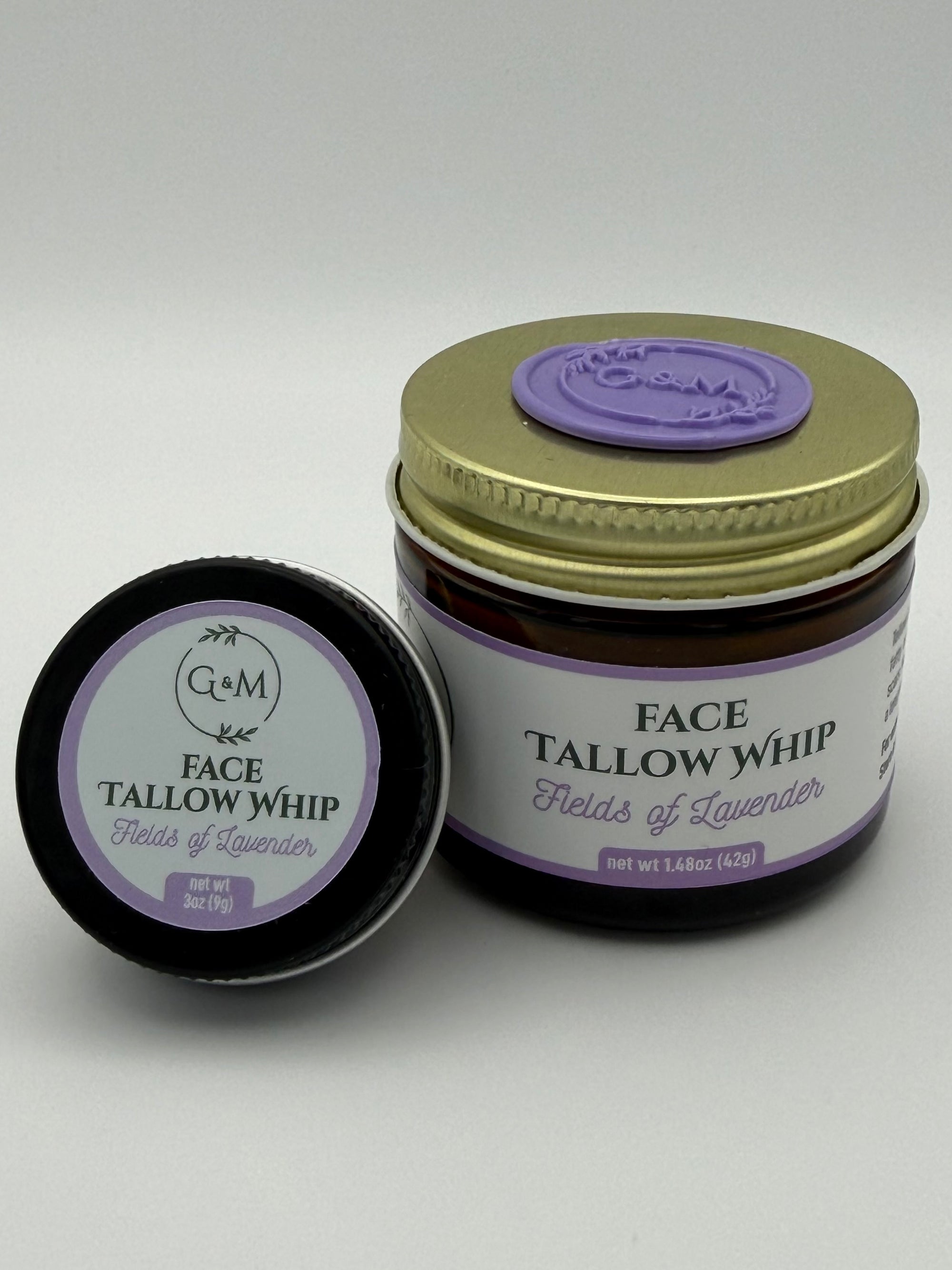 Lavender Face Tallow Whip jar with gold lid and purple wax seal on it and black travel tin on a white background