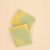 Two green and yellow soap bars on a white background