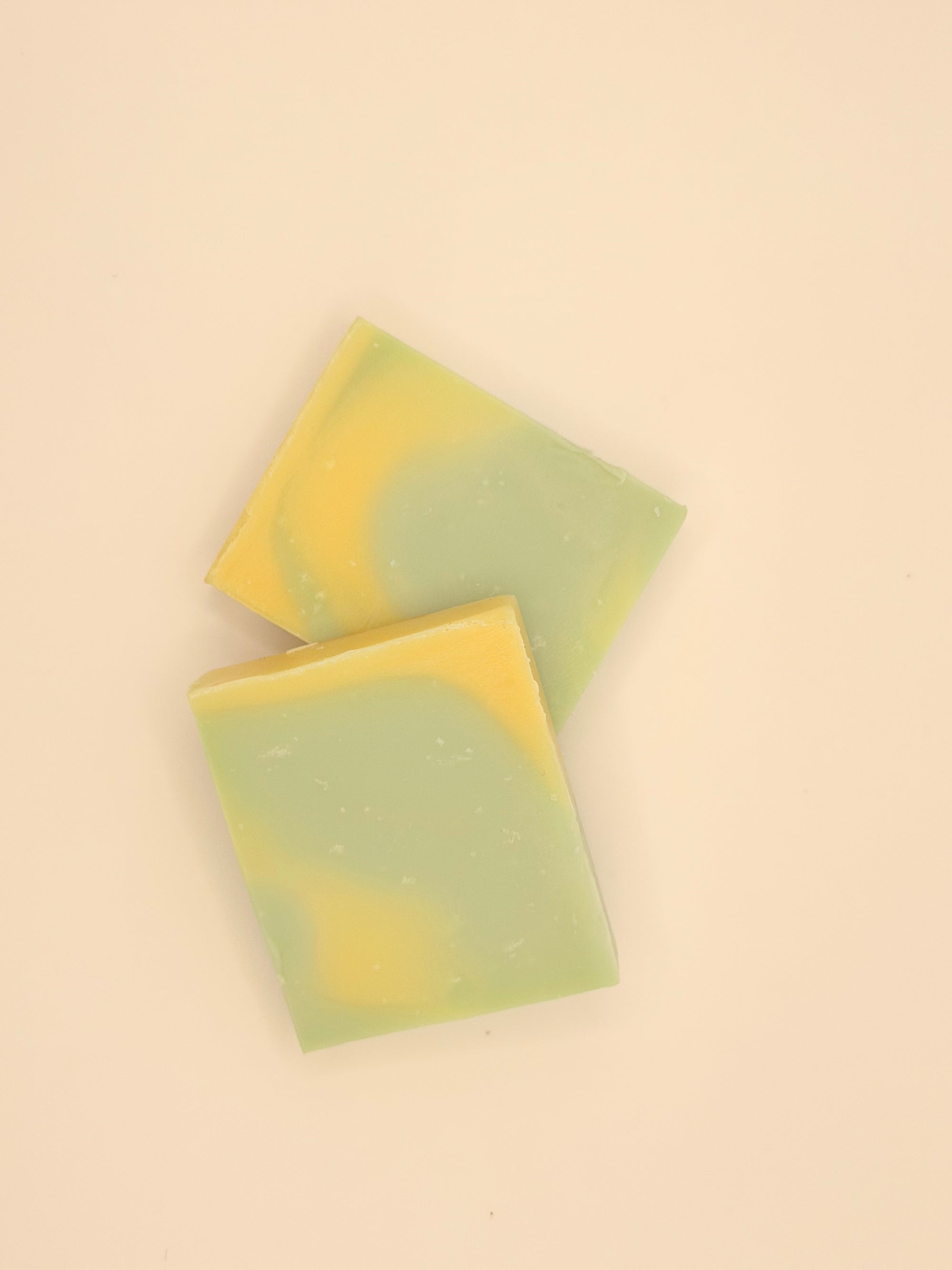 Two green and yellow soap bars on a white background